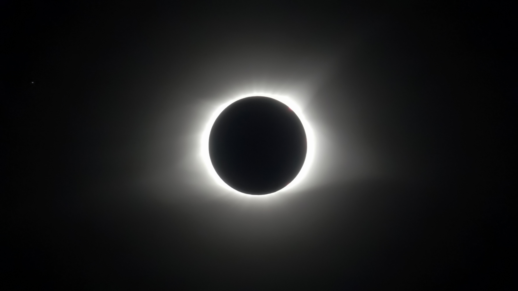 Solar eclipse with corona visible in dark sky.