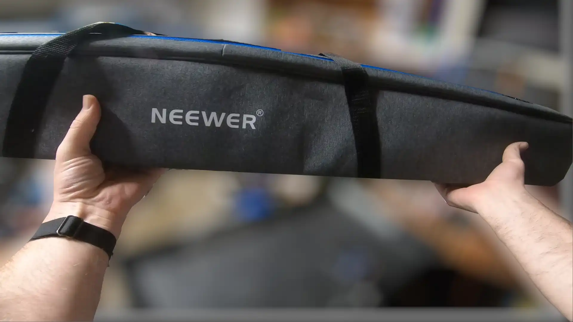 Person holding Neewer branded equipment case.